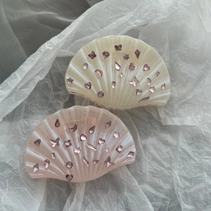 Détail de pinces à cheveux en coquillage avec perles et strass roses en forme de cœur et étoile