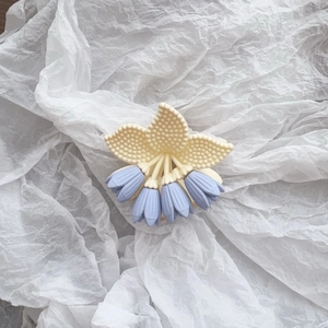Detail der matten Haarklammer mit cremefarbenen Tulpenblättern und blauen Blüten