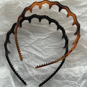 Detail view of anti-slip wavy teeth combs on black and amber tortoiseshell headbands