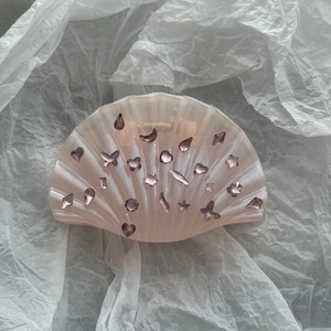 Détail d'une pince à cheveux en forme de coquillage rose avec des paillettes colorées