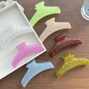 Macro shot of colorful acrylic hair claws with embedded rhinestones on a wooden surface