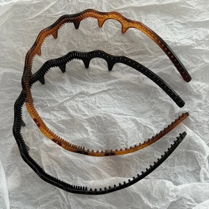 Detail view of wavy non-slip hairbands with inner teeth in black and amber resin