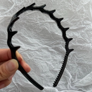 Close-up of black plastic headband with integrated small clips for hairstyle styling