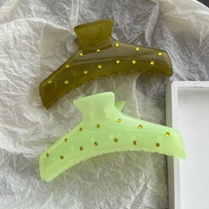 Close-up of olive and lemon green hair claws with sparkling yellow rhinestones