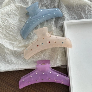 Three colorful rhinestone shark hair claws in pastel blue, pink, and purple shades