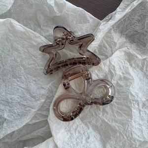 Detail of star and bow shaped translucent brown acrylic hair claws with rose gold springs