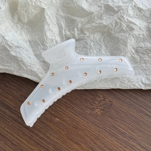 Detailed macro view of large cream resin hair claw clip with champagne rhinestones