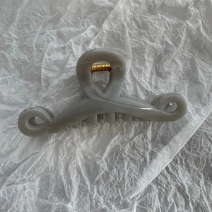 Close-up of a large grey minimalist hair claw clip with a strong gold metal spring detail