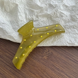 Detail of translucent green hair claw clip with sparkling yellow rhinestones