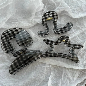 Detail view of four checkered pattern hair claws with gold metal springs on white paper