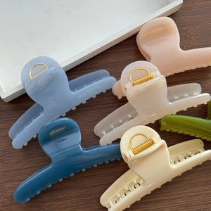 Close-up of matte butterfly spring hair claws in six soft pastel colors on a wood surface
