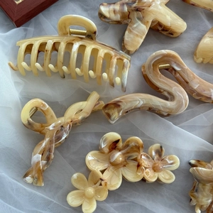 Selection of amber acetate hair claws in various vintage shapes on white fabric