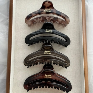 Close-up of four large French claw clips in tortoiseshell and solid colors on a tray