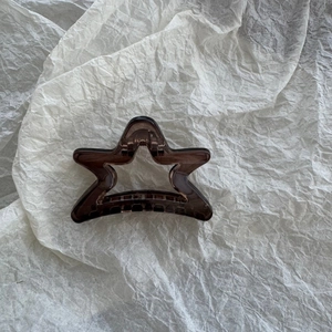 Detail view of a translucent brown star-shaped hair claw clip with metal spring