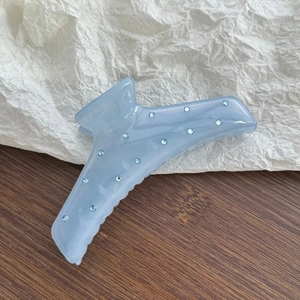 Detail of light blue translucent hair claw clip with rhinestones on a wooden background