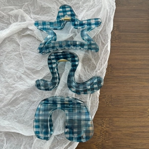 Detail of blue and white gingham hair claws in star, curved, and arc shapes