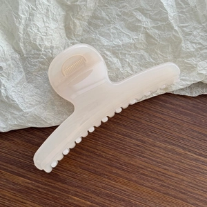 Detail view of a cream white butterfly spring hair claw clip on wooden background