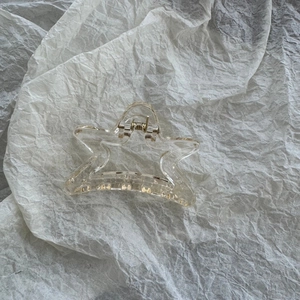 Macro detail of a clear star-shaped hair claw clip with visible golden metal spring