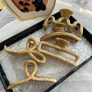 Dettaglio di quattro mollette per capelli effetto marmo su un vassoio decorativo chic