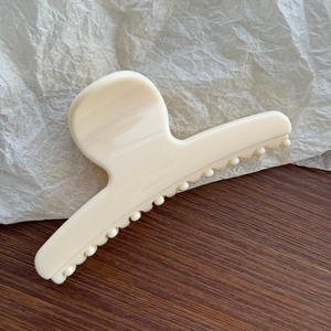 Close-up of a large cream-colored claw clip with smooth texture for thick hair styling