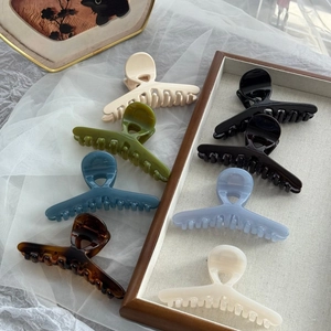 Variety of glossy French hair claws in various colors displayed on a rustic wooden tray