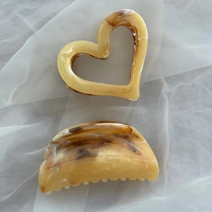 Close-up of heart and crescent-shaped amber acetate hair claws on white fabric