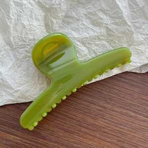Detail view of a translucent olive green hair claw clip with smooth acrylic finish