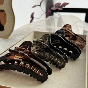 Elegant large hair claw clips in tortoise shell and solid colors on a luxury tray