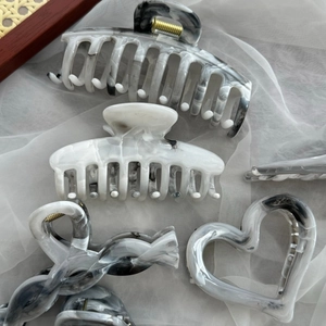 Elegante Haarklammern-Kollektion aus Acetat mit Tintenmarmor-Muster auf weißem Schleier