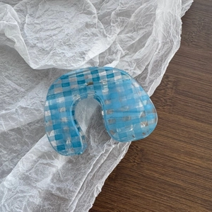Detailed top view of a large U-shaped hair claw with light blue and white plaid pattern