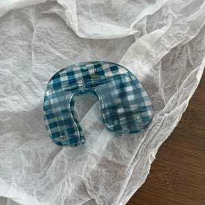 Detailed view of U-shaped blue and white gingham hair claw clip with internal metal spring