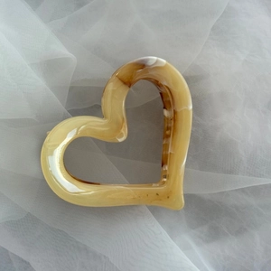 Close-up of heart-shaped hair claw with yellow ink marble texture on white tulle fabric