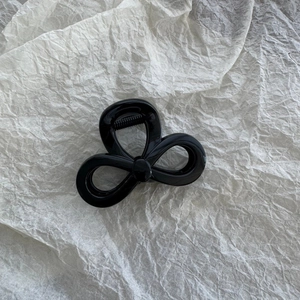 Close-up of glossy black star-shaped hair claw clip on textured beige background