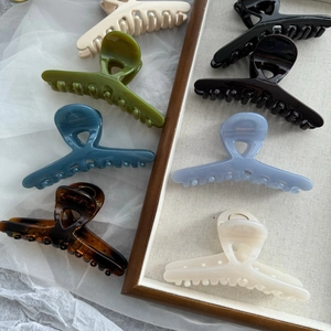Detail showing various colors of glossy hair claw clips in elegant French crossover design