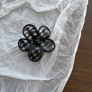 Detail of five-petal flower hair claw clip with black and white checkered pattern inlay