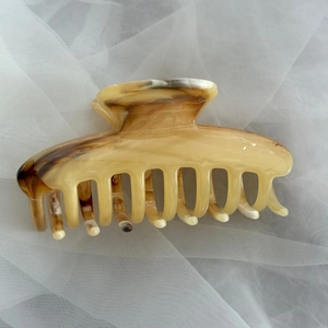 Detail view of large amber pattern acetate hair claw clip with vintage ink texture