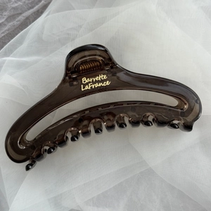 Close-up of a large translucent coffee brown hair claw clip with French style gold lettering