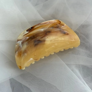 Detailed view of large amber resin hair claw clip with vintage ink-wash texture on mesh