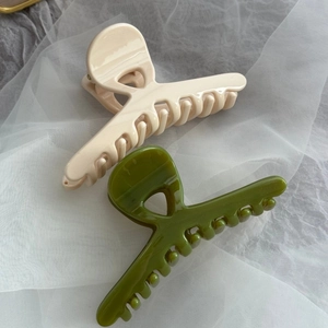 Glossy cross-shaped claw clips in cream and olive green on elegant lace background