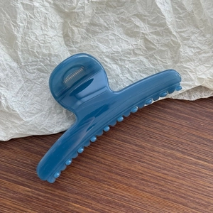 Detail view of a matte blue butterfly spring hair claw clip with large acrylic teeth