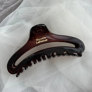 Close-up of tortoise shell resin hair claw with elegant gold Barrette LaFrance text