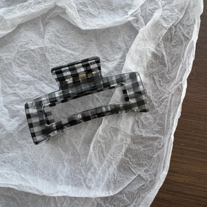 Detail view of rectangular black and white checkerboard hair claw clip with gold spring