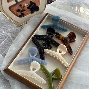 Elegant large hair claw clips set in assorted colors displayed on a luxury wooden tray