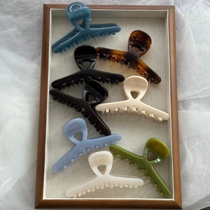 Close-up of elegant glossy hair clips in various colors arranged on a wooden tray