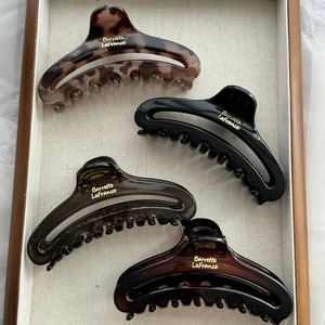 Detail of four matte and tortoiseshell French style hair claws in a wooden tray