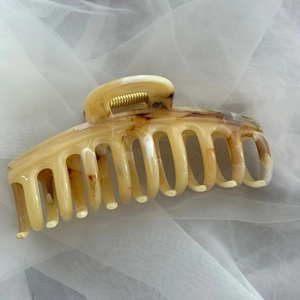 Detail of premium acetic acid hair claw clip with amber marble texture and gold spring