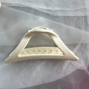Detail view of large cream-colored silicone hair claw clip with gold metal spring for women