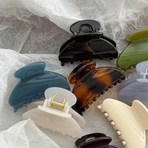 Close-up of elegant small fan-shaped hair claws in various glossy colors and patterns