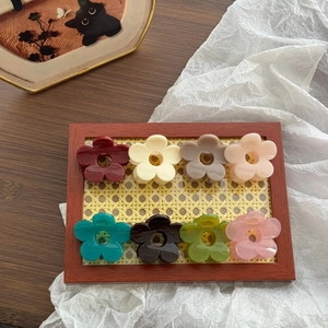 Set of 8 floral claw clips in assorted colors on a wooden tray for hairstyling