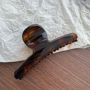 Close-up of a large amber tortoiseshell hair claw clip with smooth glossy finish